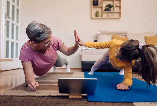 Zwei Frauen geben sich beim Online-Workout zu Hause ein High-Five